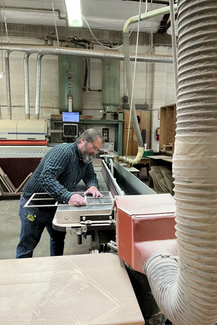 Home 3 Craftsman sanding custom wood cabinet piece in Elite Cabinetry & Granite workshop