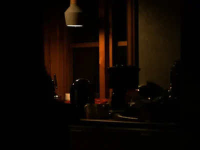 A warm, dimly lit kitchen with wood cabinetry and stainless steel appliances at night.