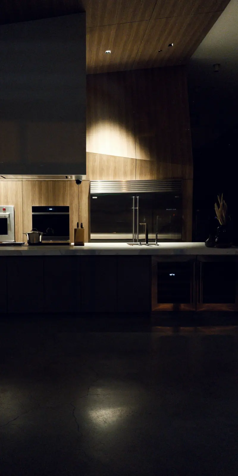 Dark kitchen illuminated only by a small pendant light over the sink at night.
