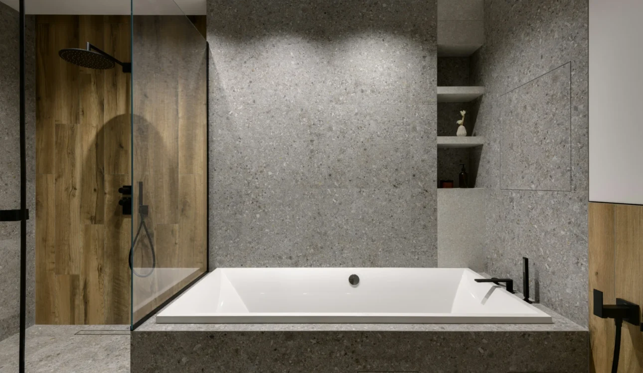Built-in soaking tub with textured stone and walk-in shower