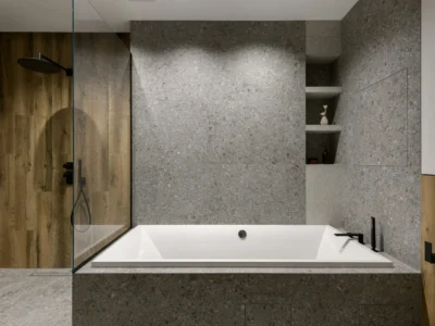 Built-in soaking tub with textured stone and walk-in shower
