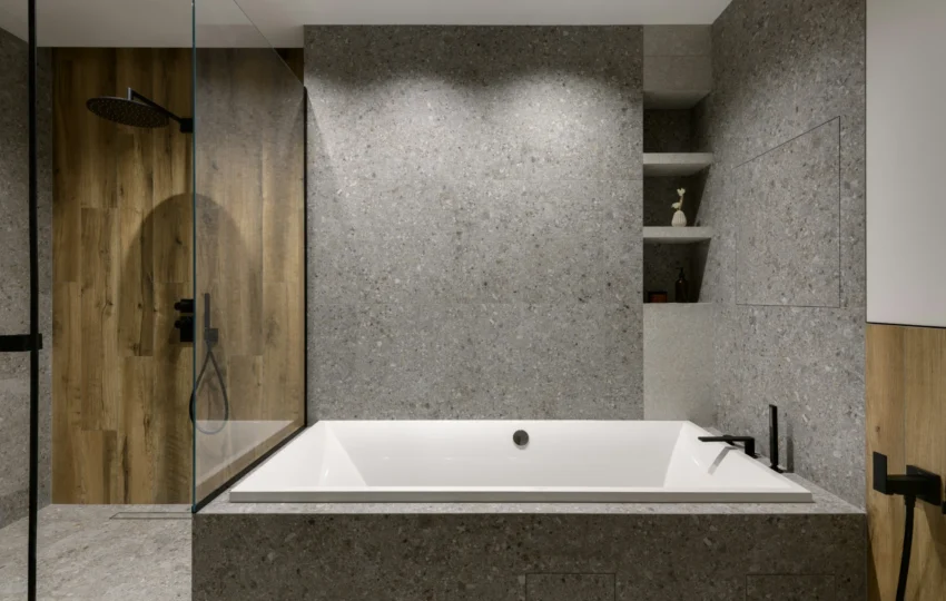 Built-in soaking tub with textured stone and walk-in shower