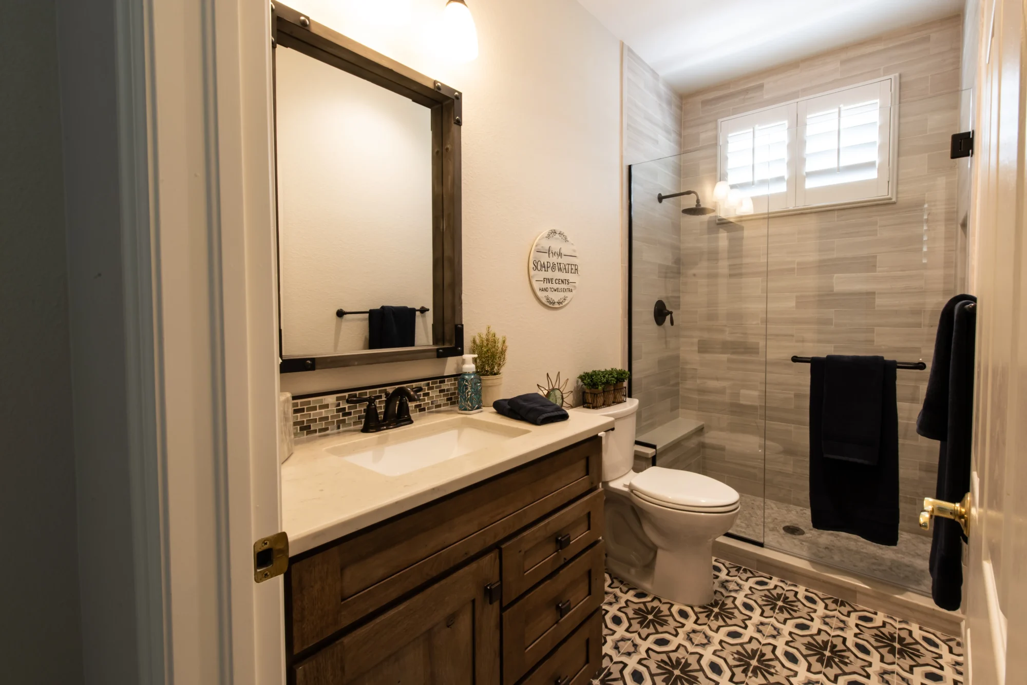 Compact bathroom remodel with patterned floor tile and walk-in shower