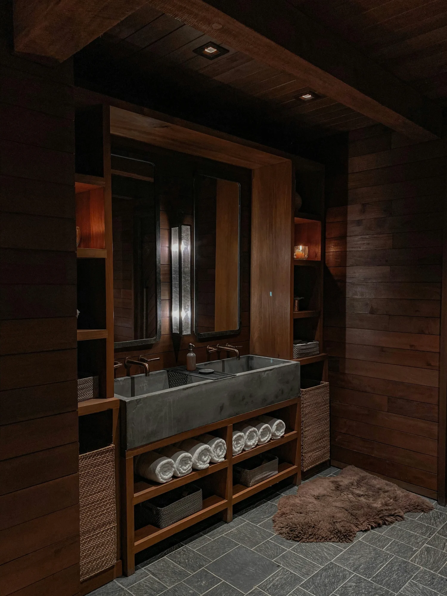 Dark wood spa bathroom with floating vanity and warm ambient lighting