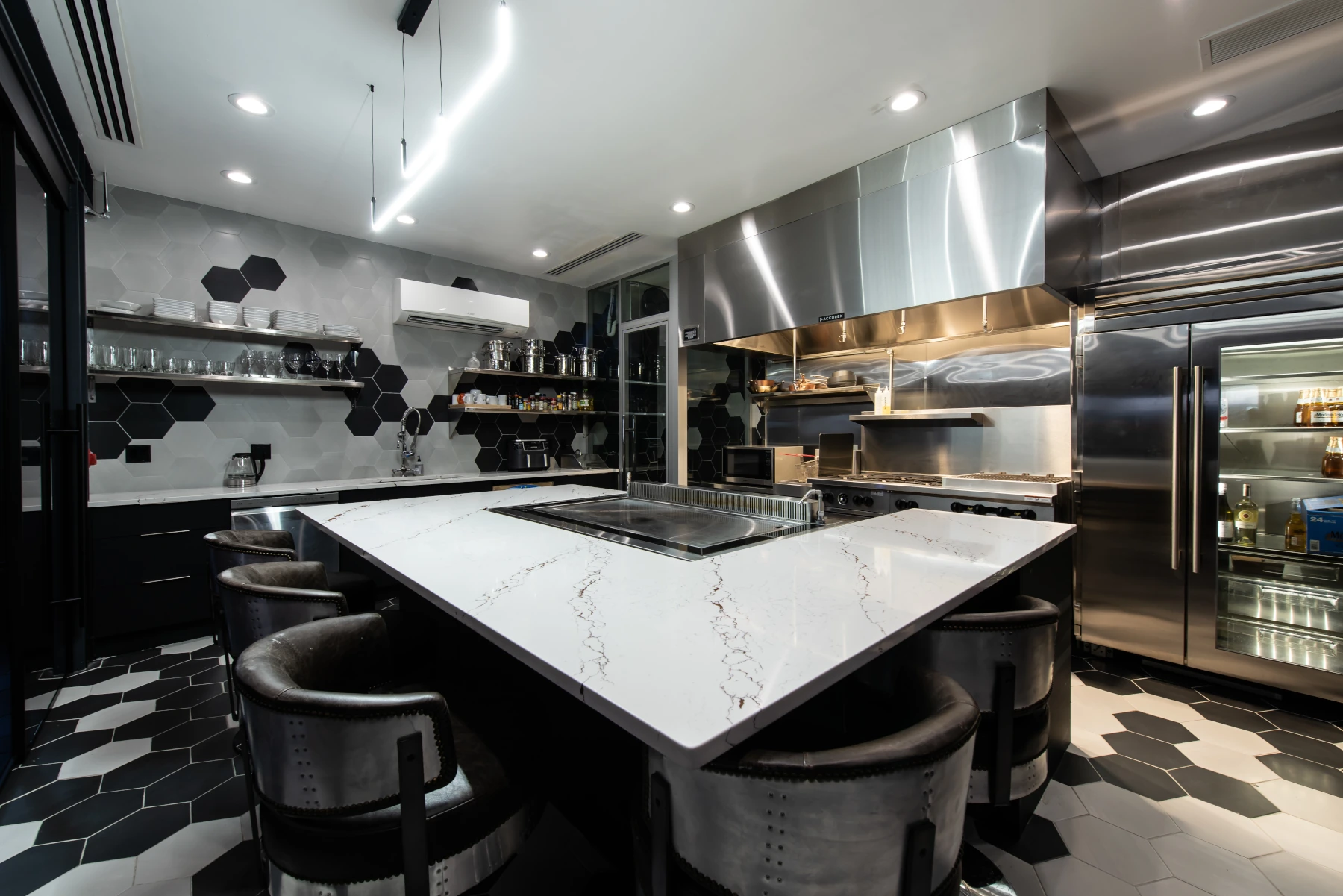 Warm kitchen with marble kitchen island, wood cabinets, gold pendant lights, and exposed brick wall