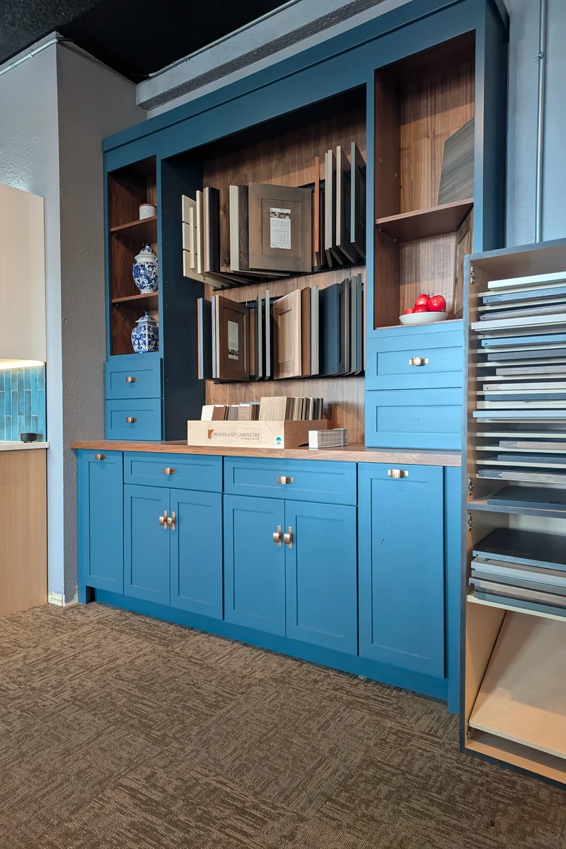 Blue showroom hutch with cabinet door samples, drawer hardware, wood shelving, and finish sample displays.