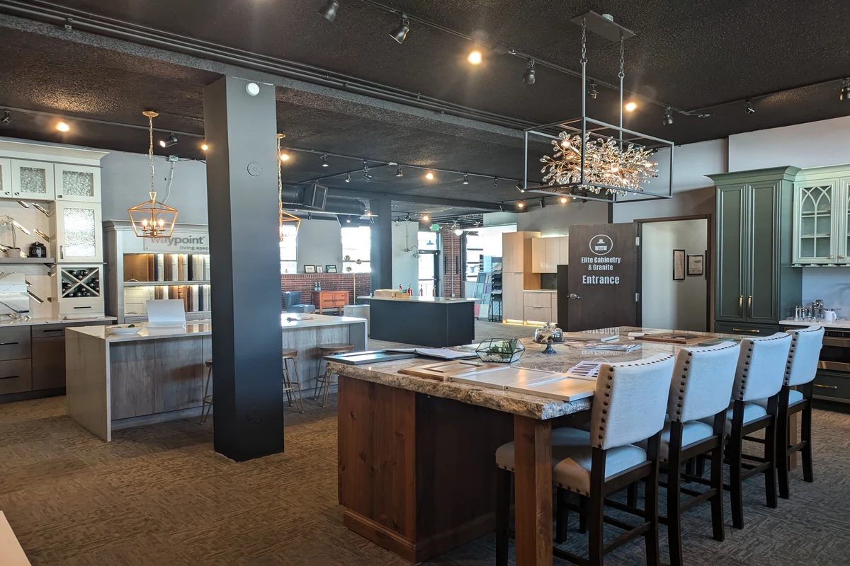 Elite Cabinetry & Granite showroom floor with kitchen displays, island seating, cabinetry samples, lighting fixtures, and design areas.