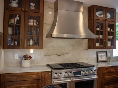 Burnished Grain Kitchen 6 Burnished Grain Kitchen stainless range hood and gas range with walnut glass front cabinets and marble backsplash