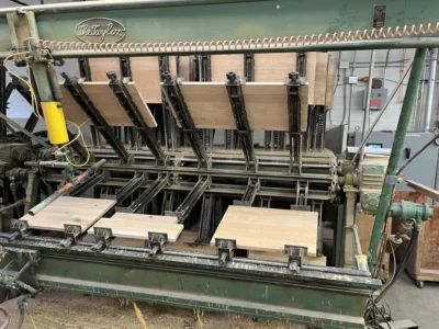 Industrial glue press machine assembling custom wood cabinet panels in a Denver cabinetry workshop.