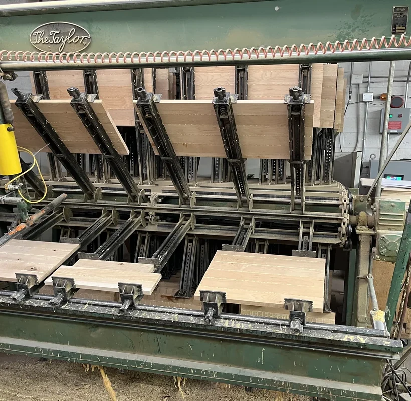 Industrial glue press machine assembling custom wood cabinet panels in a Denver cabinetry workshop.