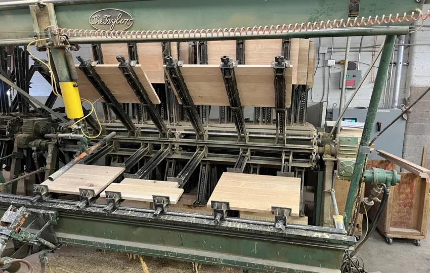 Industrial glue press machine assembling custom wood cabinet panels in a Denver cabinetry workshop.