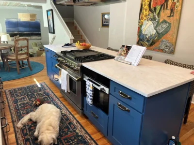 Large blue kitchen island with a white marble-look countertop, professional range, and built-in microwave