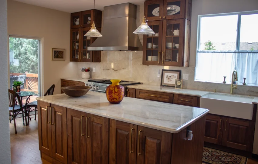 Light stone countertop on a kitchen island with dark wood cabinets and pendant lighting